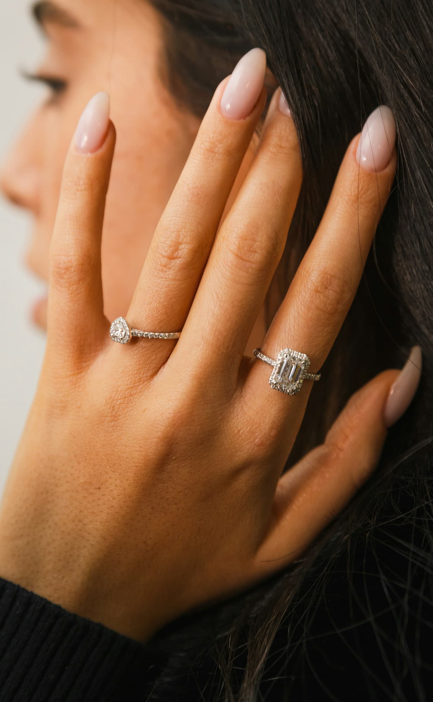 Emerald-cut solitaire and a pear ring worn on a hand