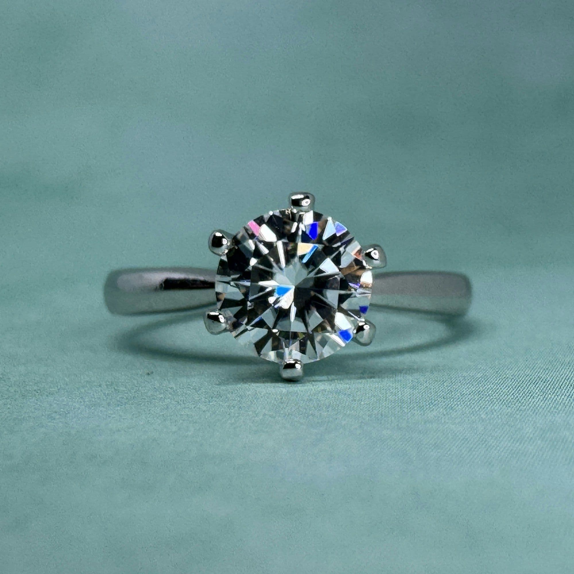 Round brilliant solitaire in six prongs on teal silk