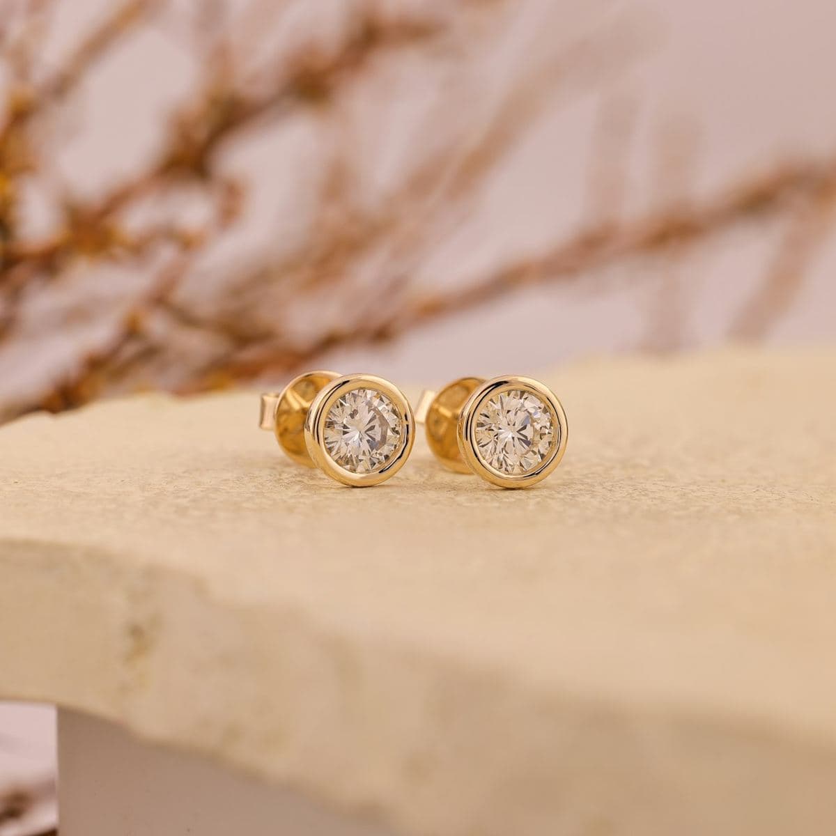 Pair of round solitaire studs in polished yellow-gold bezel settings