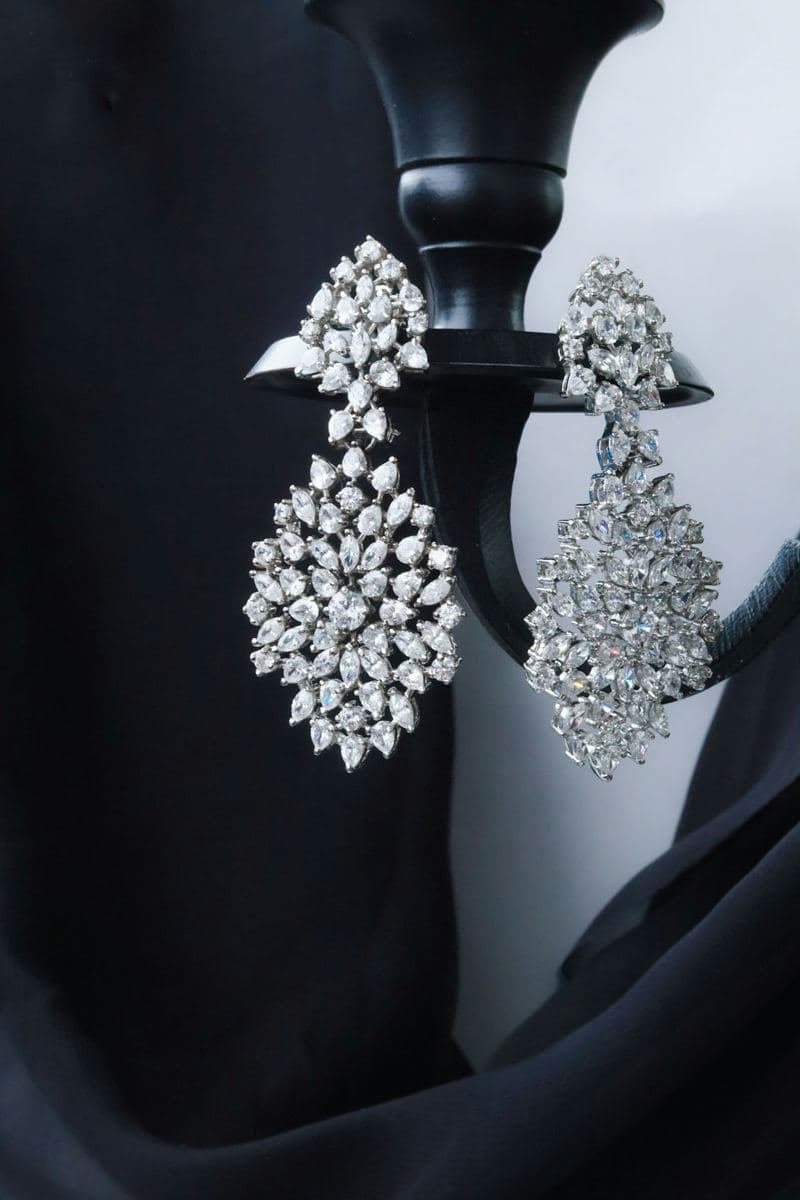 Pair of large chandelier drops of clustered marquise, pear and round stones in white metal hung on a black candlestick
