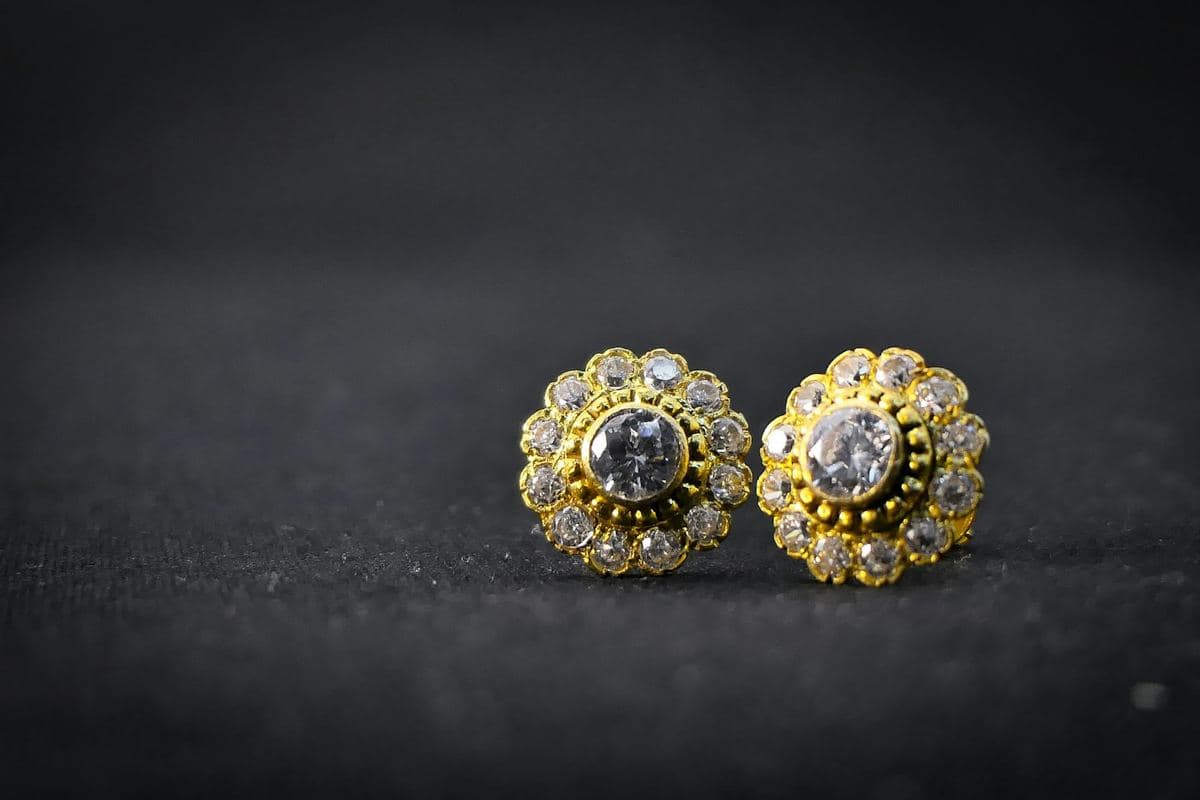 Pair of flower-shaped studs: bezel-set round center stone surrounded by twelve small round stones in yellow gold