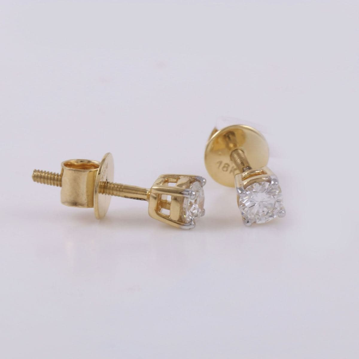 Pair of round four-prong solitaire studs with yellow-gold baskets, white prong tips and 18K-stamped screw backs
