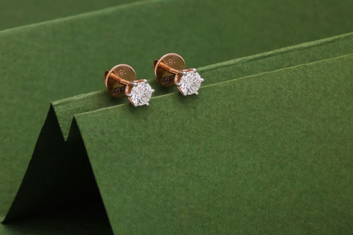 Pair of round solitaire studs in six white prongs on rose-gold screw-back posts stamped 18