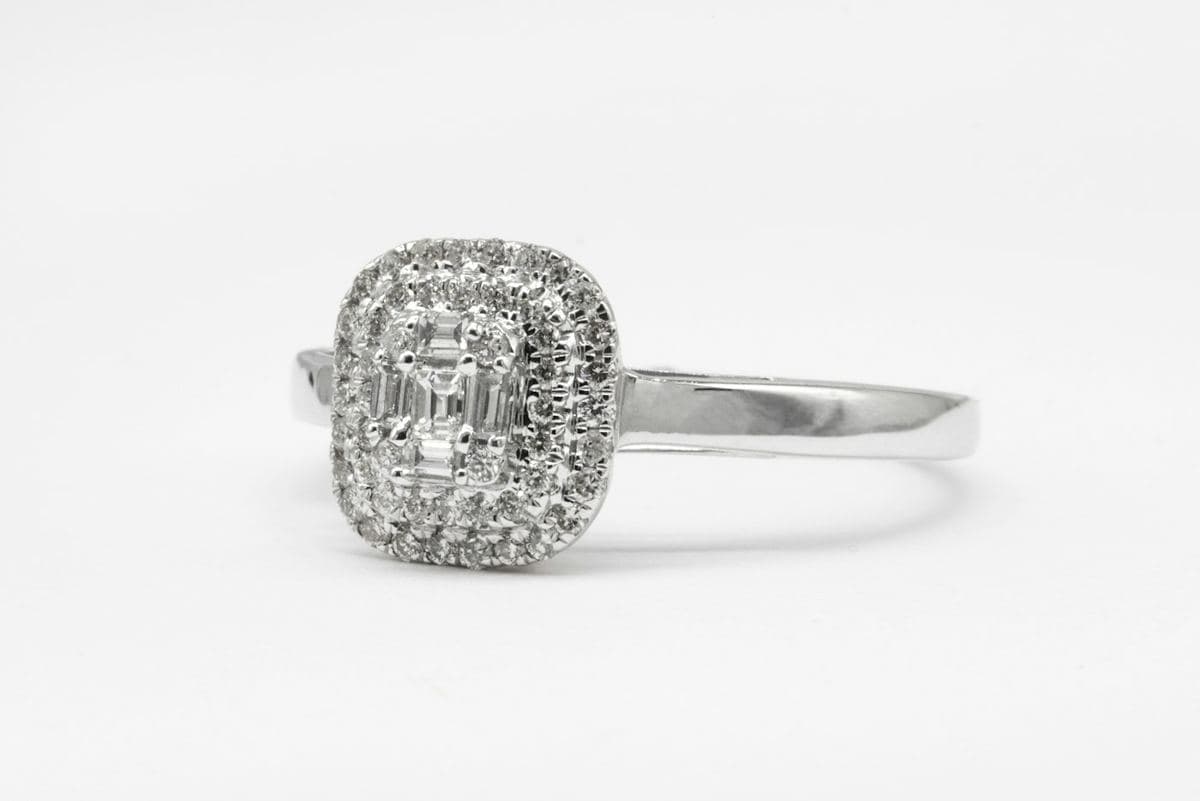 Center is a cluster of baguettes forming an emerald shape, inside a double pavé halo on a polished white band