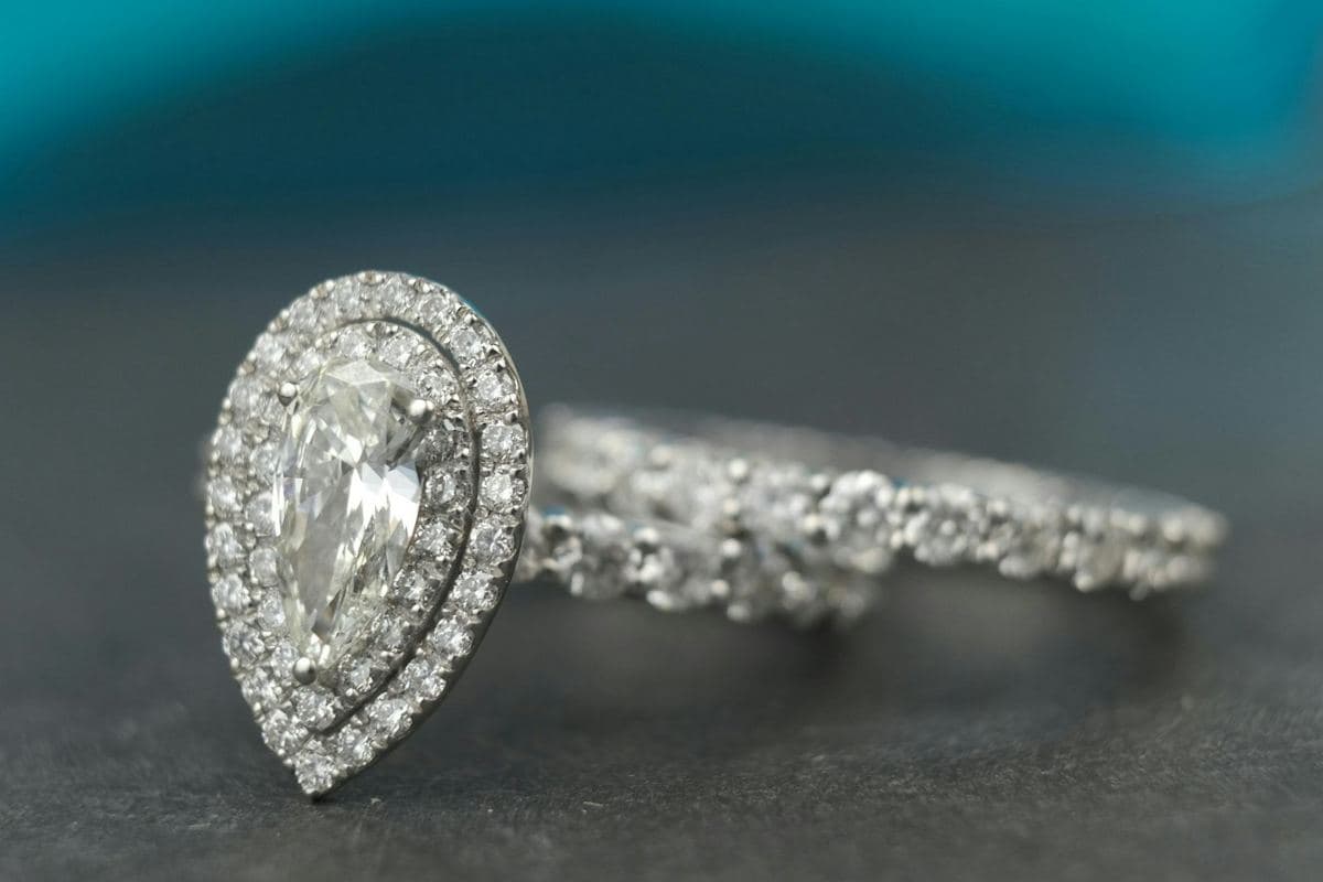 Elongated pear in a double pavé halo with a shared-prong stone band beside it