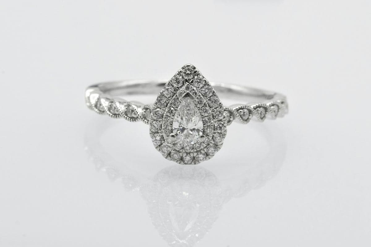 Pear center in a double pavé halo on a scalloped milgrain stone band, white metal