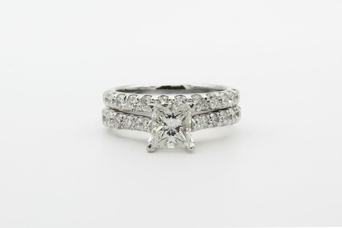 Princess-cut center in four V-prongs on a shared-prong stone band, stacked with a matching stone wedding band (bridal set)
