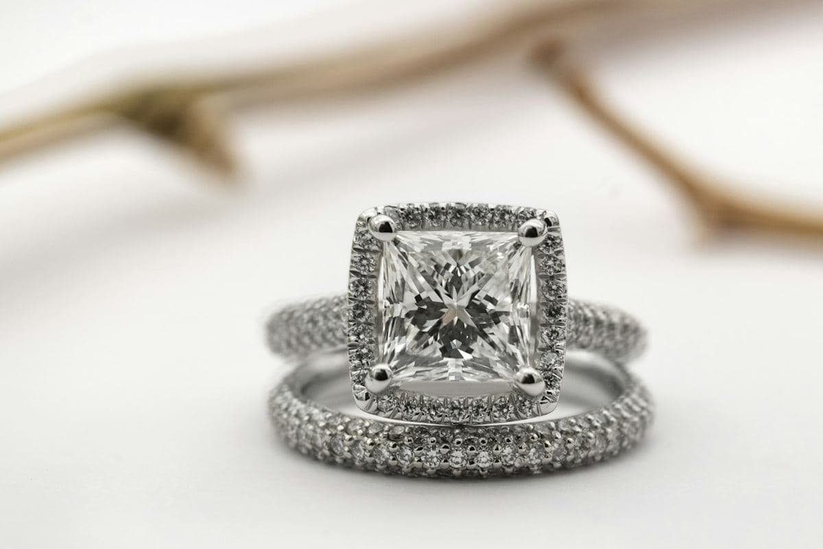 Large princess-cut center in a square pavé halo on a pavé band, stacked with a matching pavé band