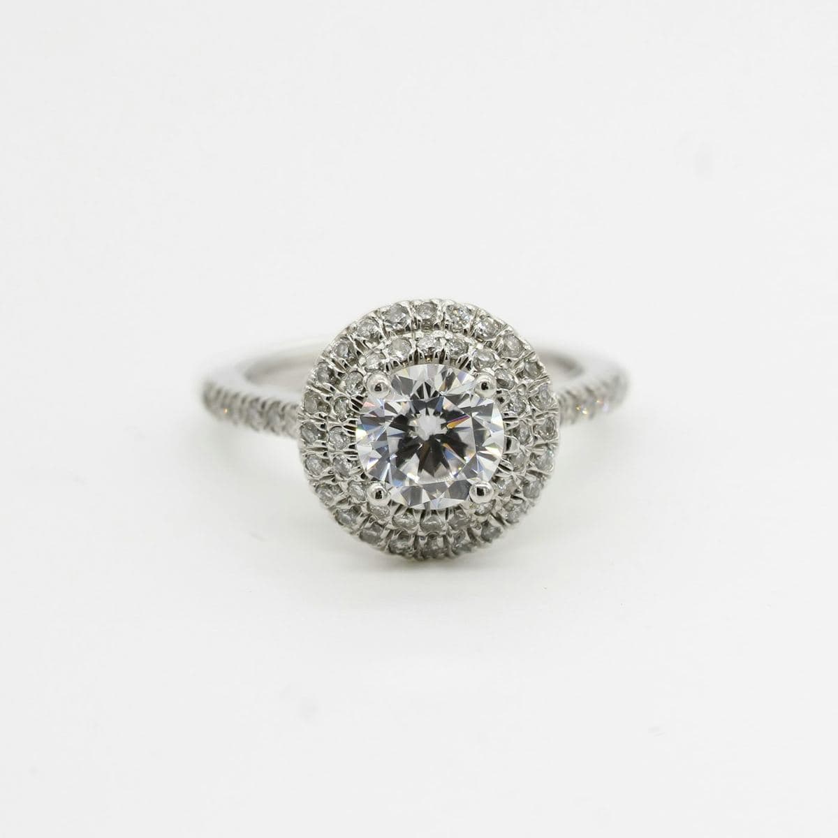 Round center in four prongs within a double pavé halo on a pavé white band