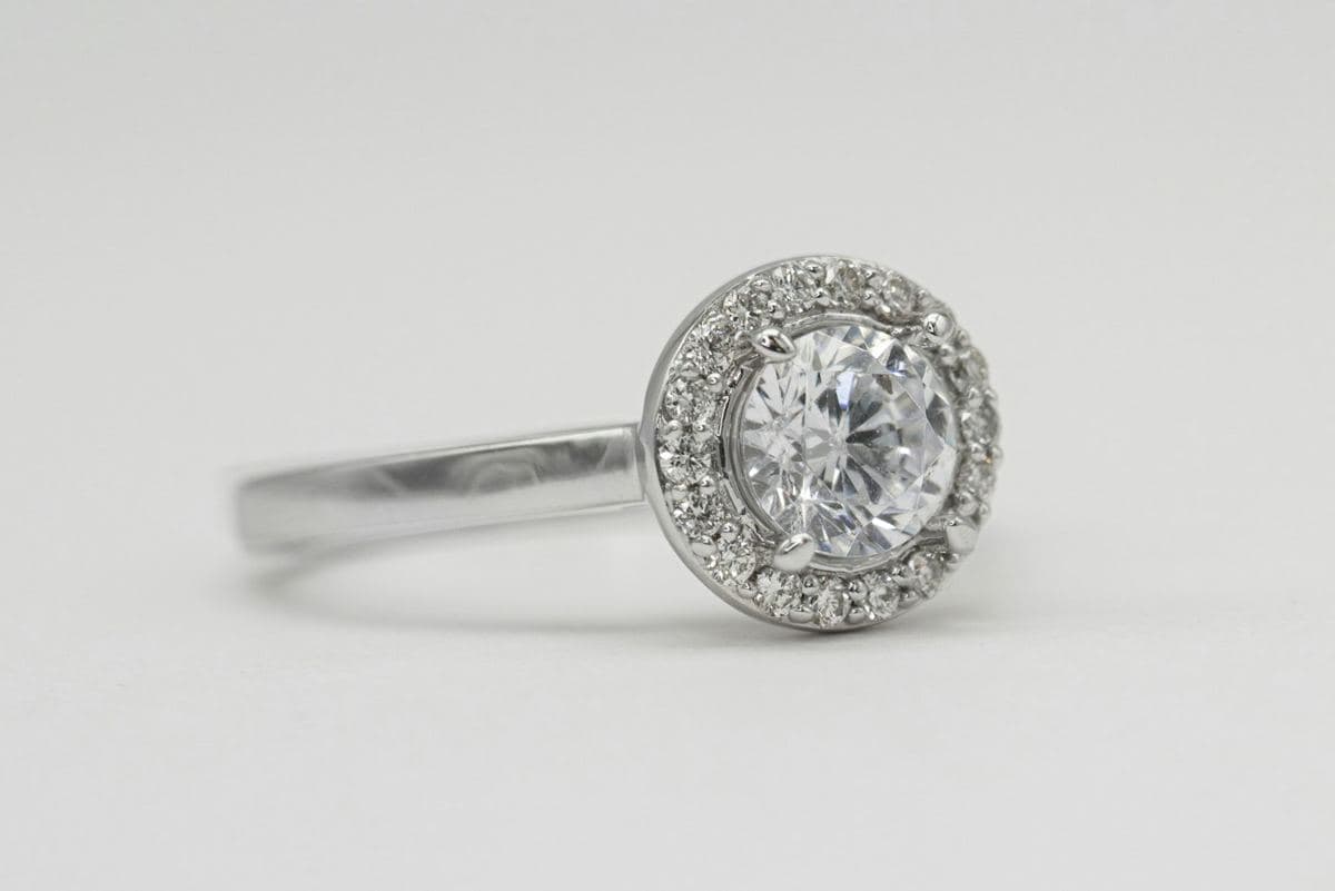Round center in four prongs inside a single pavé halo on a polished white band