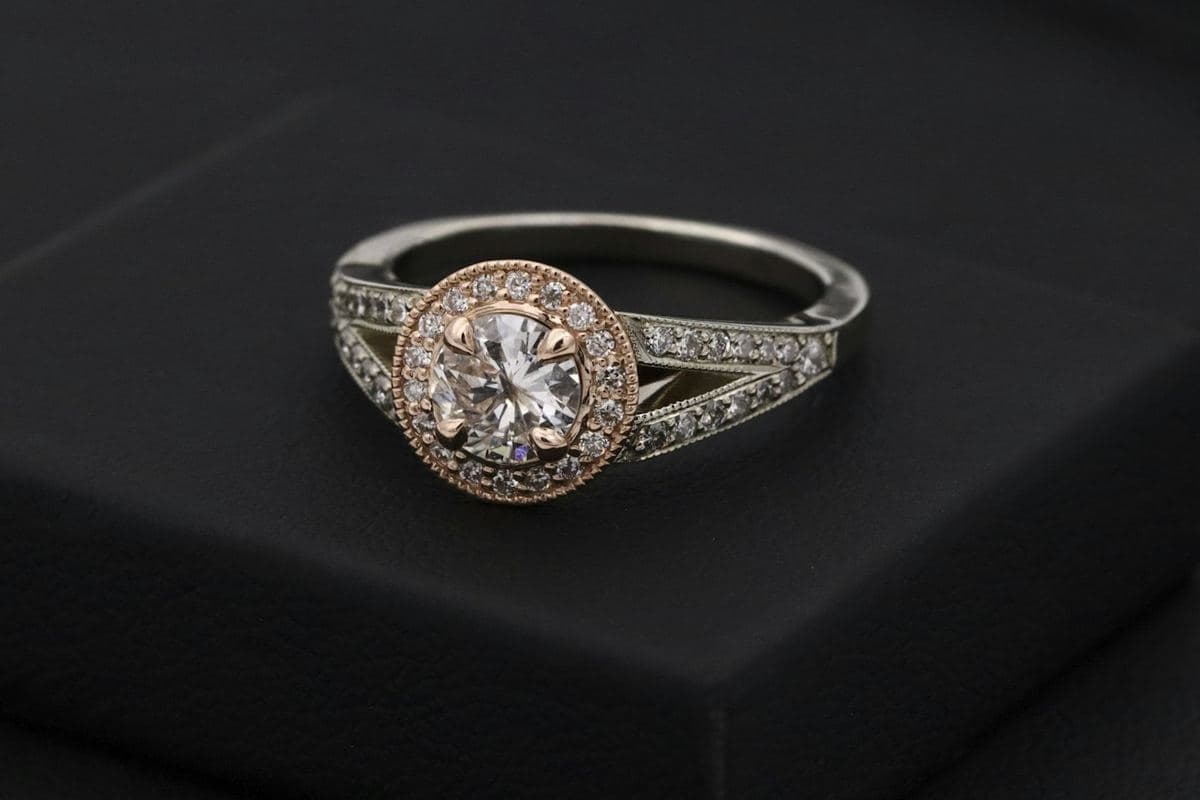 Round center in a rose-gold milgrain halo atop a white-gold split shank lined with pavé stones