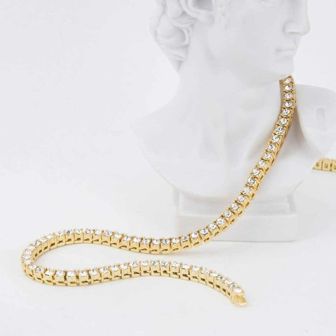 Yellow-gold tennis chain draped from a white bust