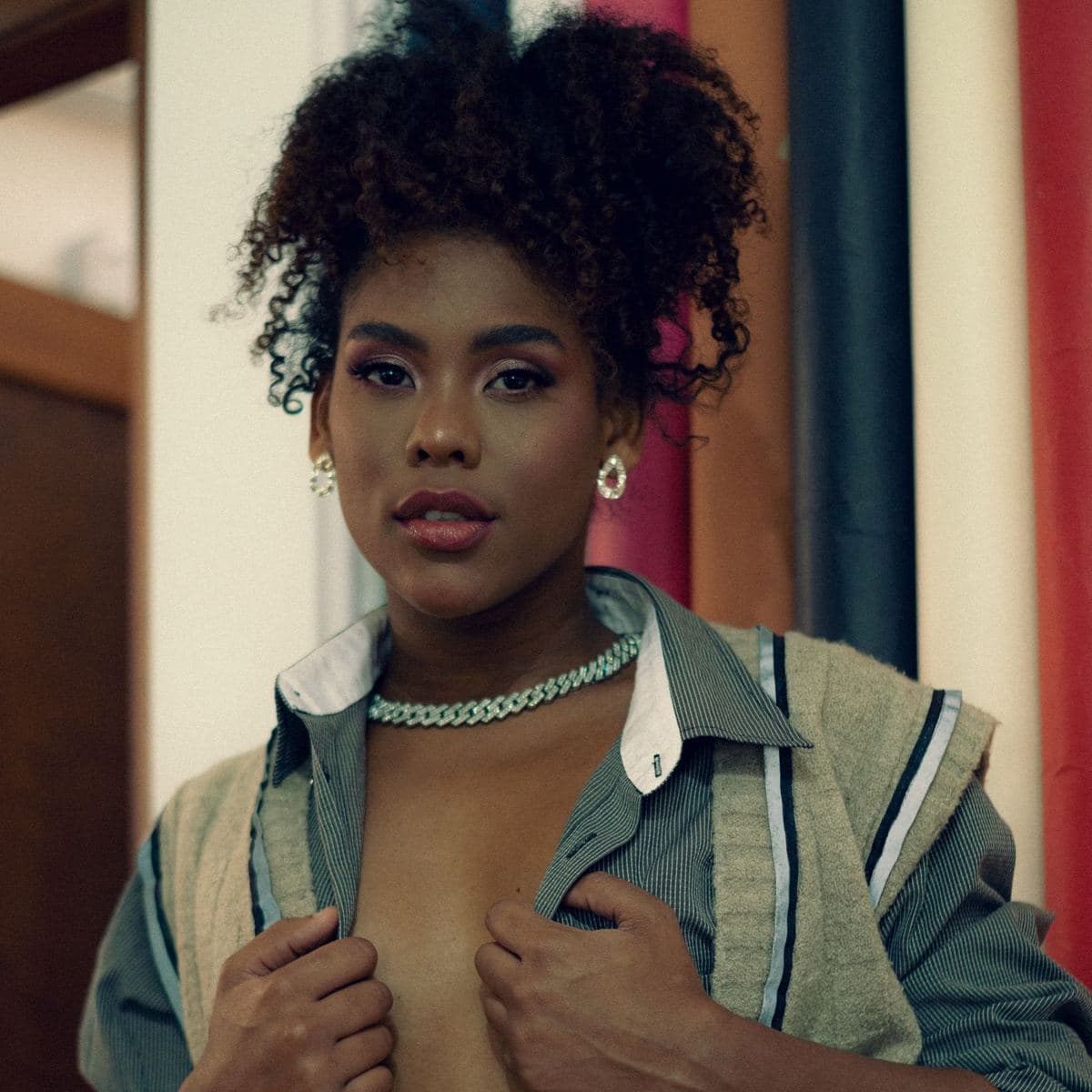 Woman in an open striped shirt wearing a white-metal fully paved cuban link chain at choker length
