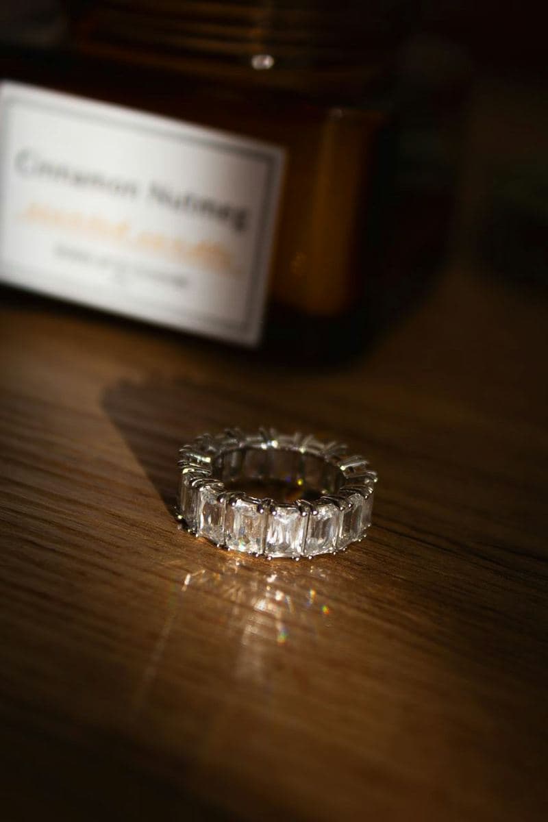 A white-metal eternity band of large emerald-cut stones in claw prongs going fully around