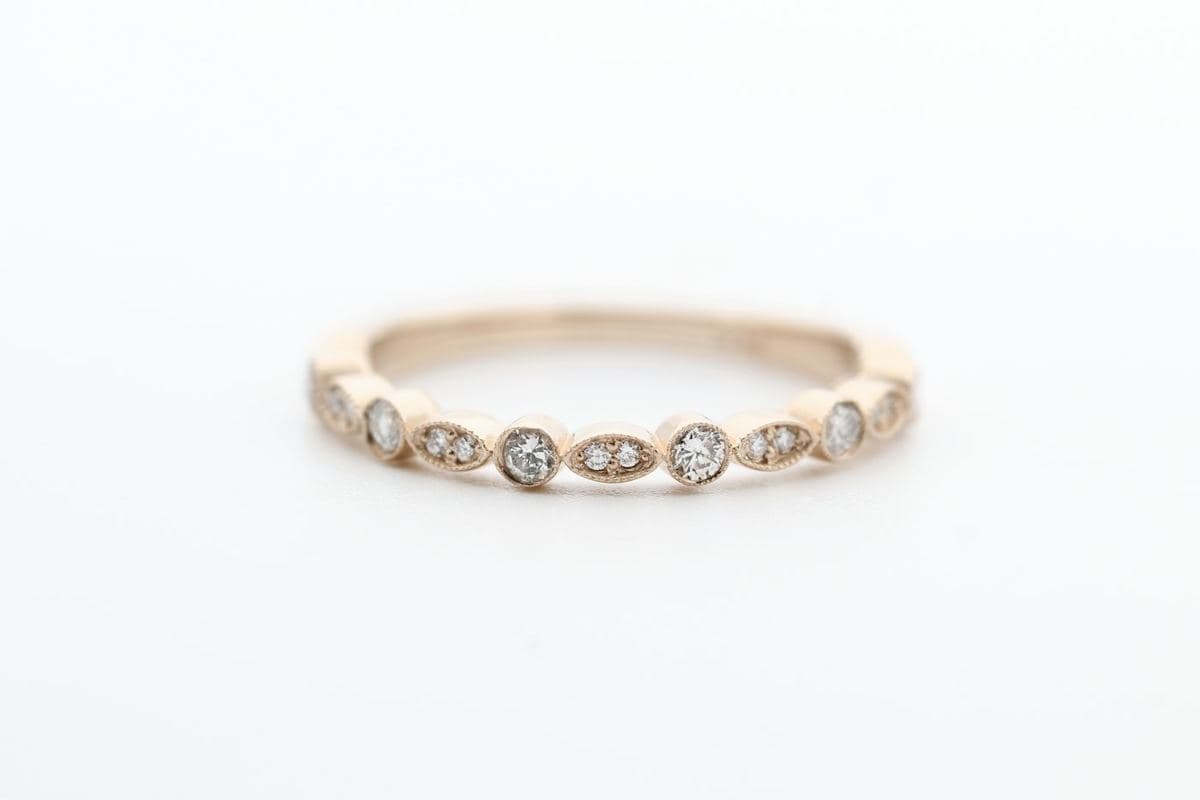 A thin rose gold band with alternating milgrain bezel-set round stones and marquise stations across the front