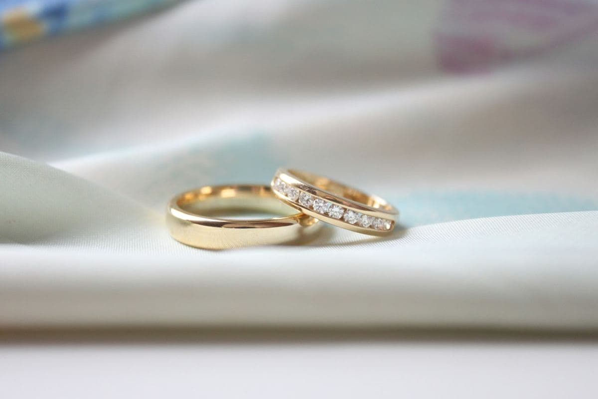 A plain polished yellow gold band beside a yellow gold channel-set round stone band