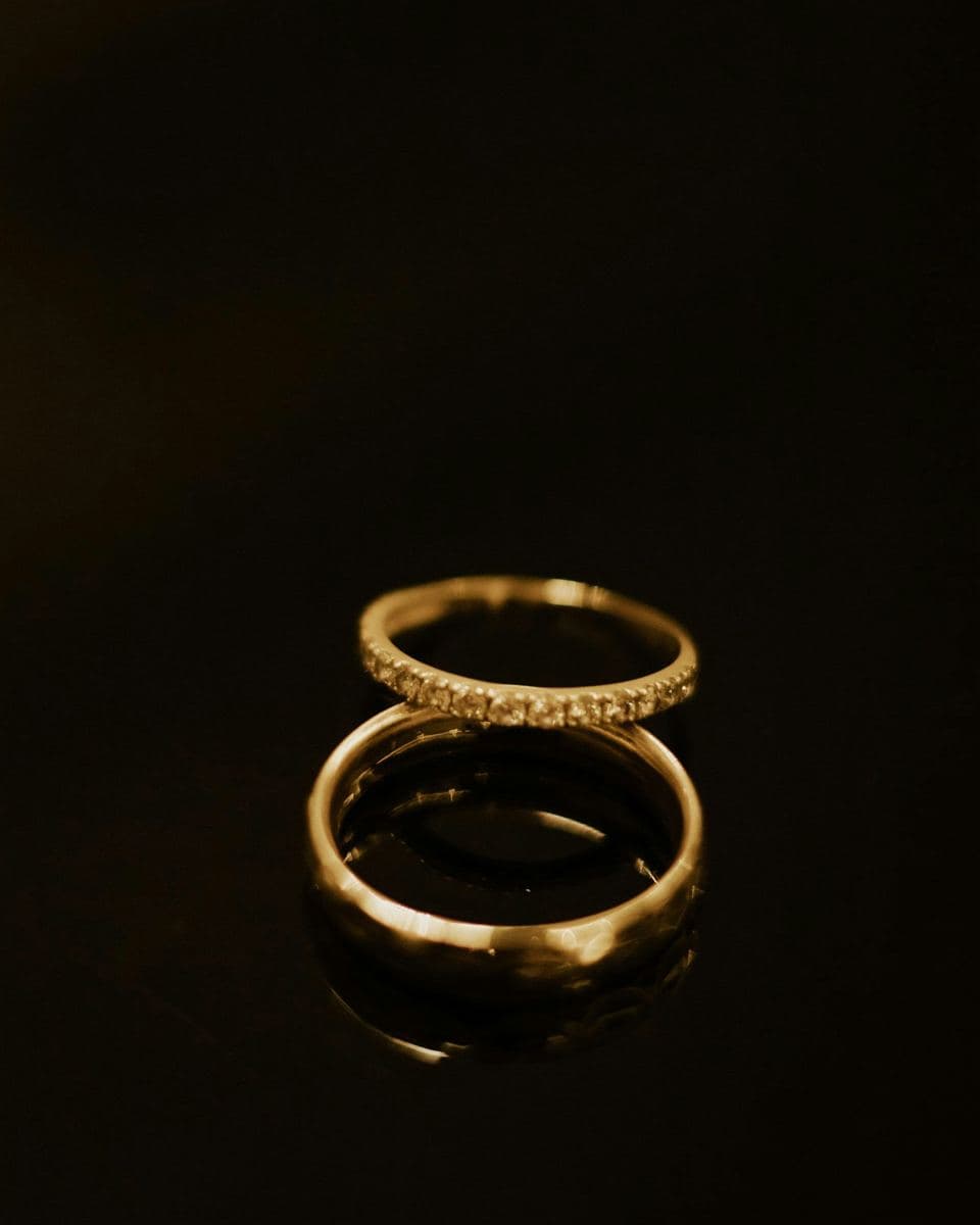 A plain polished yellow gold band with a thin yellow gold pave stone band resting on top