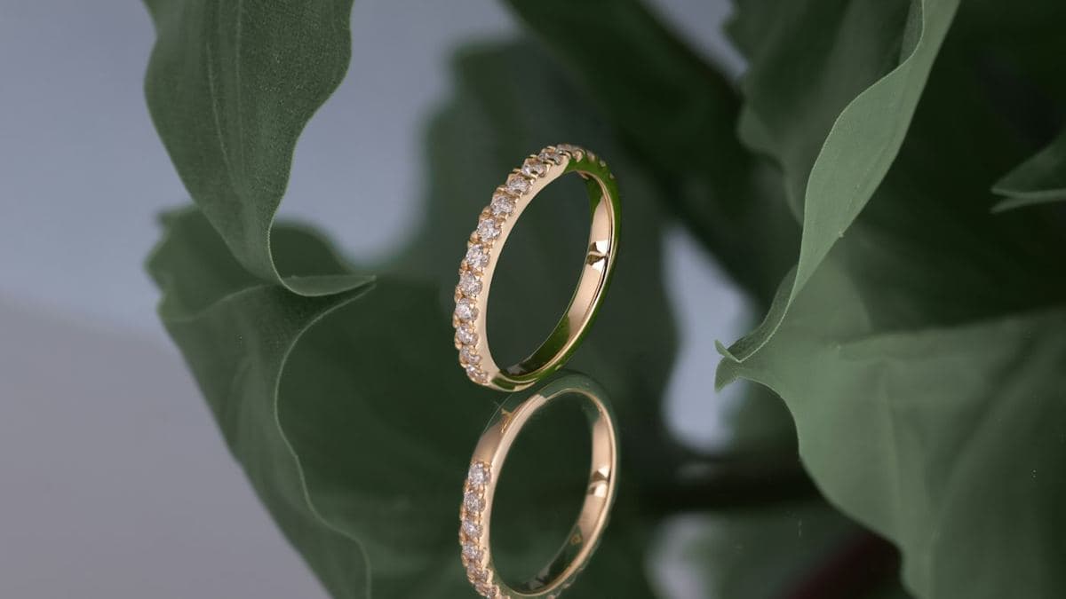 A thin yellow gold band with prong-set round stones across the front half and plain metal at the back