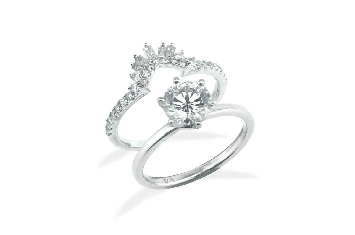 Round six-prong solitaire on a plain white-metal shank paired with a contoured crown band of baguettes and round stones