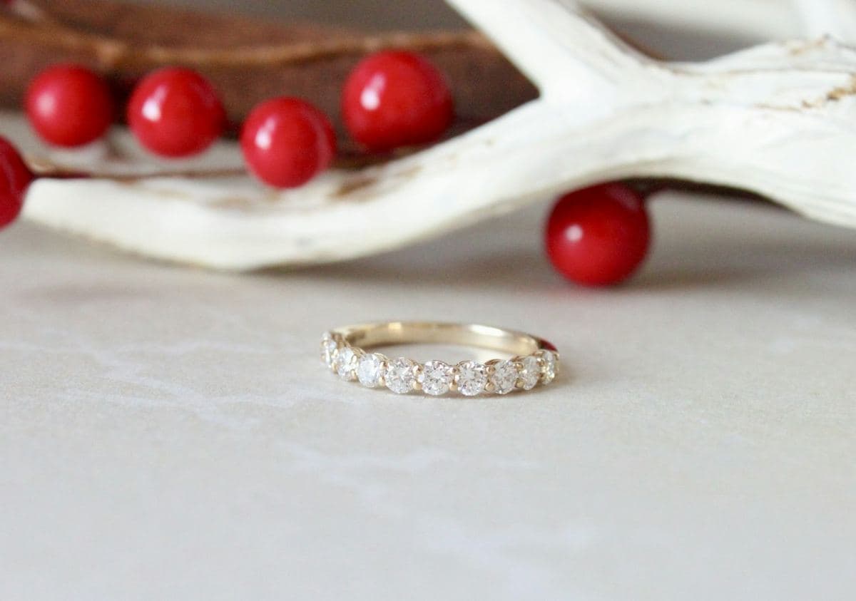 A yellow gold band with shared-prong round stones across the front and plain metal at the back