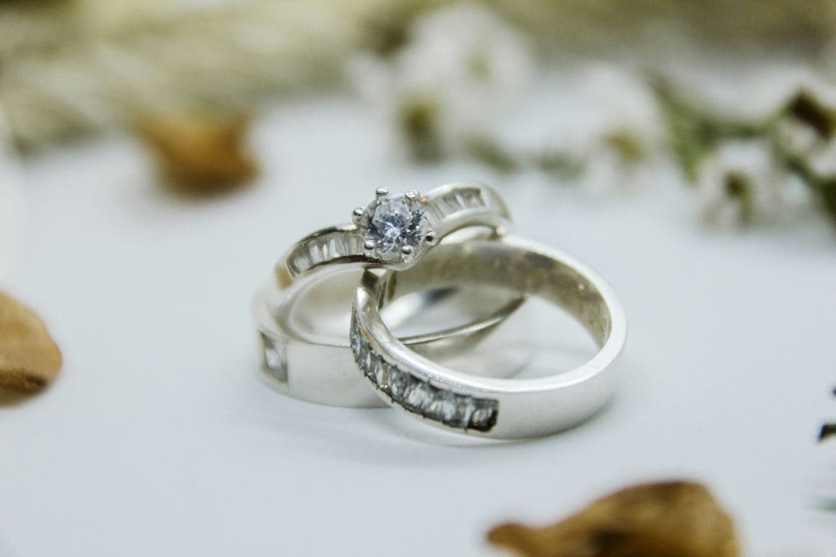 White-metal round six-prong solitaire with channel-set baguette shoulders, stacked with a wide matching band channel-set with baguettes