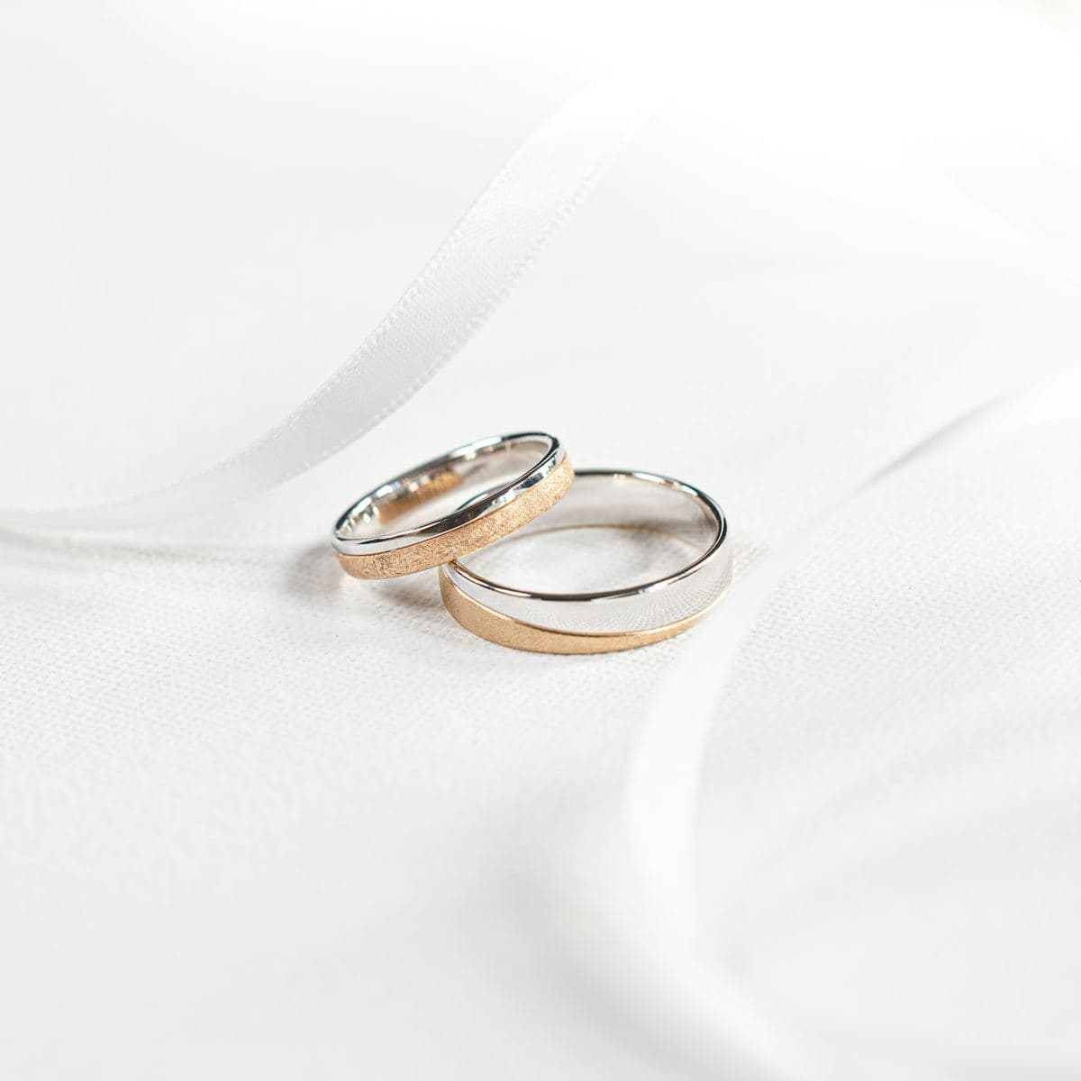 Two two-tone bands, each half polished white gold and half sandblasted rose gold, one wider than the other