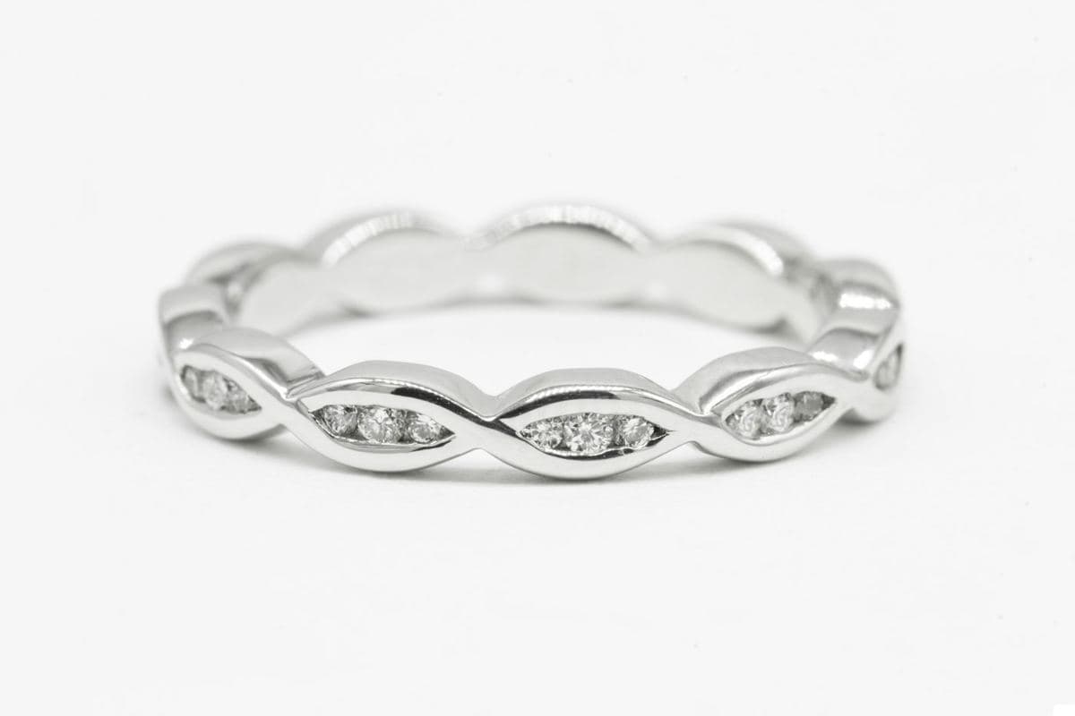 A white gold band with a twisting marquise-wave profile, small round stones channel-set inside each wave